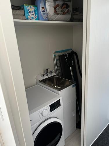 a laundry room with a sink and a washing machine at Pond Road Park - Raglan in Raglan