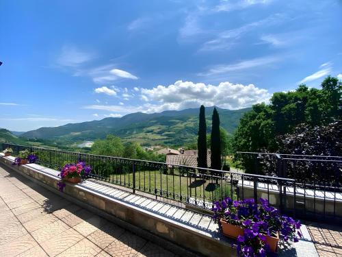a balcony with purple flowers on a fence and mountains at La Casa del Bosco - Villa con vista panoramica su Bobbio e la Val Trebbia in Bobbio