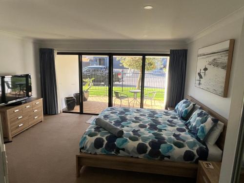 a bedroom with a bed and a sliding glass door at Moana Seaside Retreat in Moana