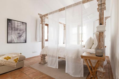 a bedroom with a bed with white curtains and a table at Cuatre Finques in Jalón