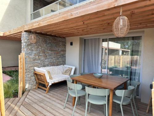 a patio with a wooden table and chairs on a deck at T4 Cala Rossa - 3 Ch - Piscine et Plage à pied in Lecci