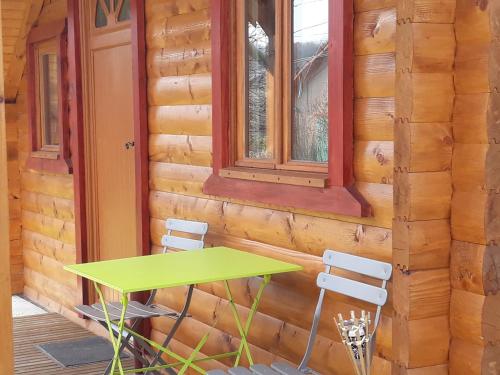 a table and chairs on the porch of a log cabin at Le petit chalet jurassien in Jouhe