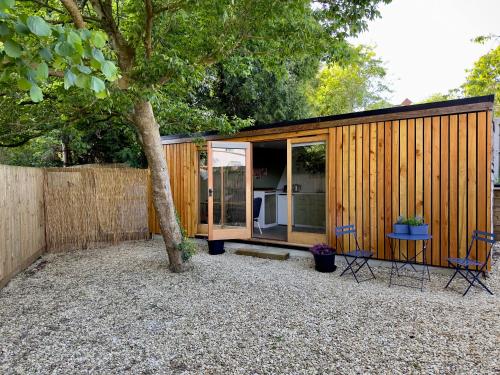 a small cabin with a tree in the backyard at The Snug: Dorset hideaway in Blandford Forum