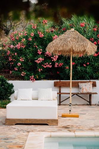 a white couch and a straw umbrella next to a pool at Cuatre Finques in Jalón