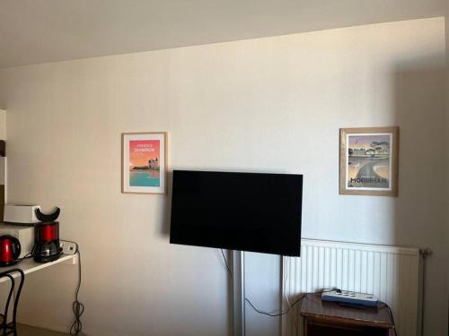 a flat screen tv on a wall with three pictures at Face à la mer studio de 33m2 avec terrasse et wifi in Larmor-Plage