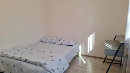 a white bedroom with a bed and a night stand at Apartman Porfido in Mostar