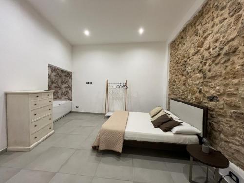 een slaapkamer met een bed en een stenen muur bij La Casa Di Eva in Siracusa