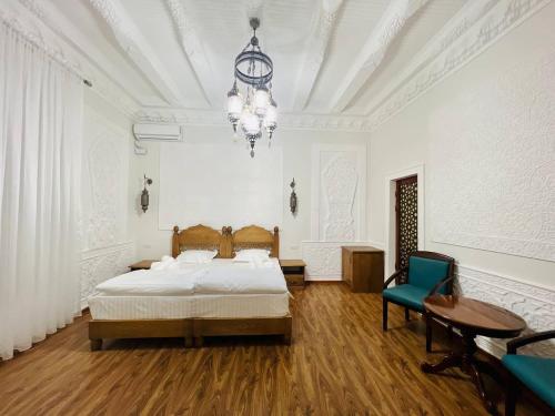 a bedroom with a bed and a table and a chandelier at Best Hotel Muqaddam in Bukhara