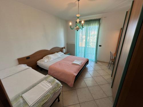 una camera con due letti e un lampadario a braccio di Residence Diana Frontemare - Agenzia Cocal a Caorle