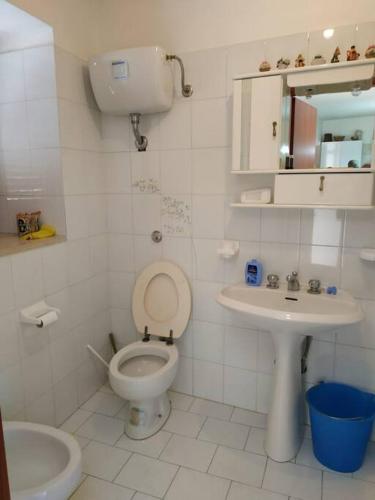 a white bathroom with a toilet and a sink at Casa Isabella Napoli in Montegiordano