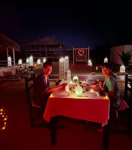 two people sitting at a table at night at Merzouga Luxurious Camp in Merzouga