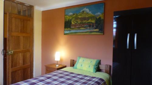 1 dormitorio con 1 cama y una pintura en la pared en Hospedaje Samana Wasi Pisac en Pisac