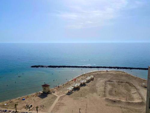a view of a beach with people in the water at Almog Haifa Israel Apartments מגדלי חוף הכרמל in Haifa