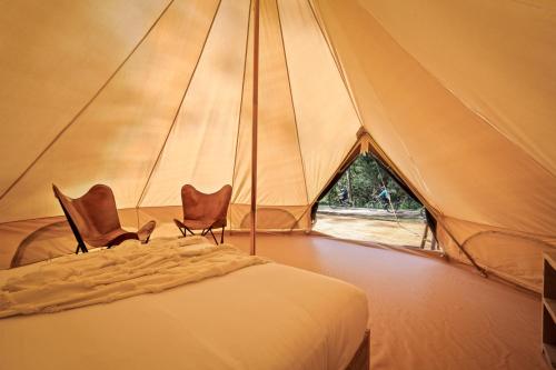 a tent with two chairs and a bed in it at Camp Crusty Eldorado in Eldorado