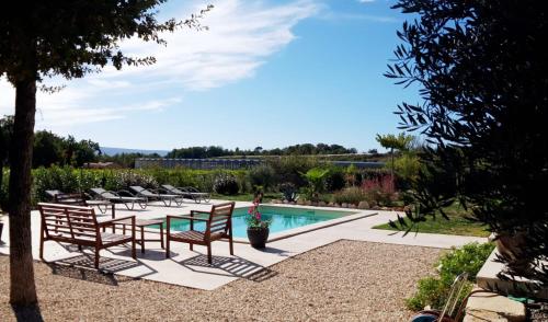 un patio avec une table et des chaises et une piscine dans l'établissement Parenthèse en Provence, à Saint-Saturnin-lès-Apt