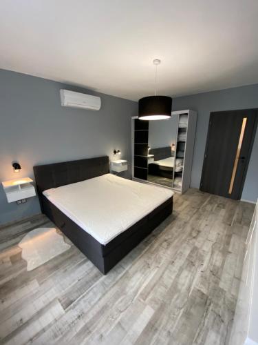 um quarto com uma cama grande e piso em madeira em Janka11 Apartman em Hódmezővásárhely