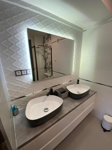 uma casa de banho com 2 lavatórios e um espelho grande em Janka11 Apartman em Hódmezővásárhely