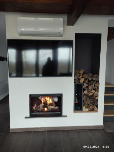 a fireplace in a living room with a pile of fire wood at Cabana NucA-Frame Baia Mare in Satu Nou de Jos