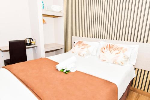 1 dormitorio con 1 cama con sábanas y almohadas blancas en Hotel Ancora Urban Center, en Finisterre