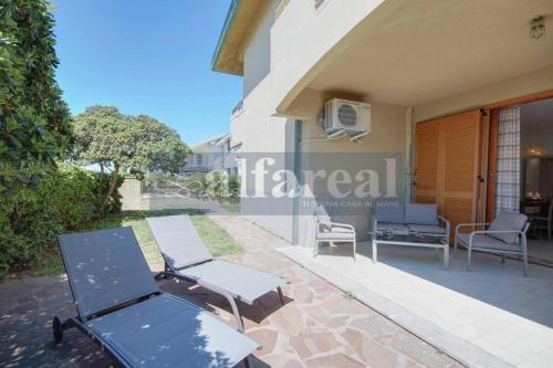 a house with two chairs and a table on a patio at Villetta MARCO POLO fronte mare con giardino e posto auto in Castiglione della Pescaia