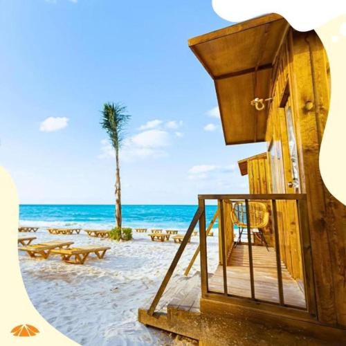Safy Bay Resort في العلمين: شاطئ به طاولات وكراسي والنخيل