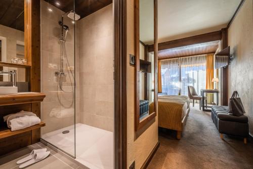 a bathroom with a shower and a bedroom at Hotel Le Samoyede in Morzine