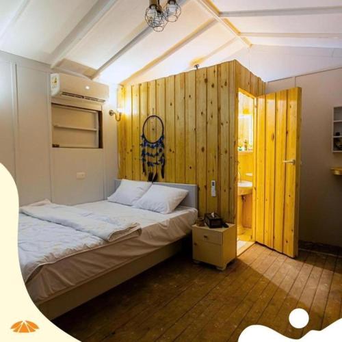 Safy Bay Resort في العلمين: غرفة نوم بسرير كبير وجدران خشبية