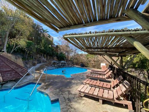 an overhead view of a swimming pool with chairs and a pergola at Thula-Thula Private Game Lodge Mabalingwe in Bela-Bela