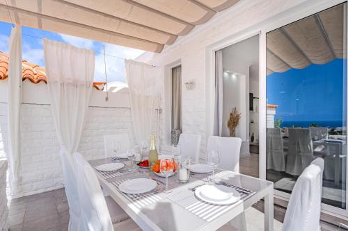 une salle à manger blanche avec une table et des chaises blanches dans l'établissement BuenaVista Romantic Bungalow in Costa Adeje, à Adeje