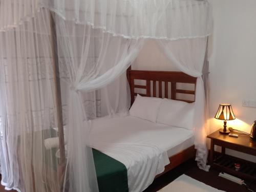1 dormitorio con cama con dosel y cortinas blancas en Wilpattu Mookalan Resort en Habawewa