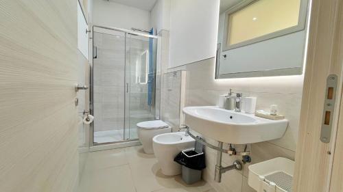 a white bathroom with a sink and a toilet at Flamingo Suites in Marina di Camerota