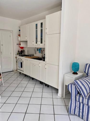 a kitchen with white cabinets and a white tiled floor at Dolcevita Villa in Vulcano in Vulcano