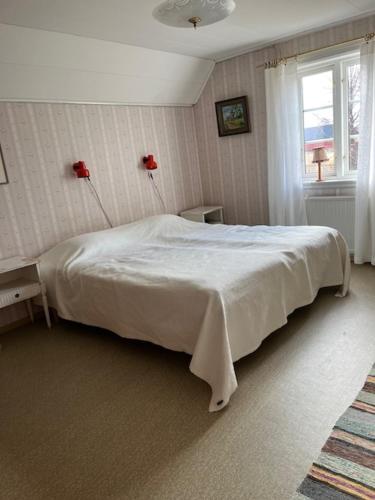 a bedroom with a white bed and a window at Åsen in Årjäng