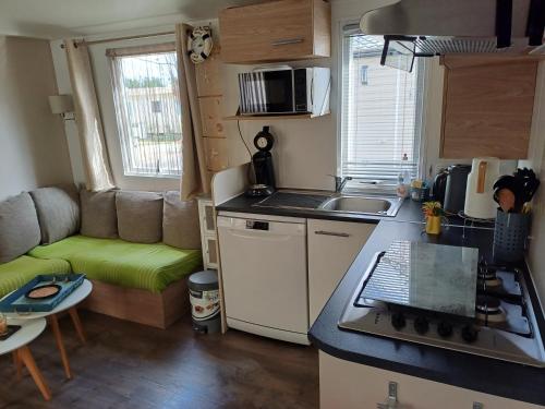uma pequena cozinha com um lavatório e um sofá numa caravana em Mobil-home a louer dans un camping **** proche de la mer et forêt em Saint-Jean-de-Monts