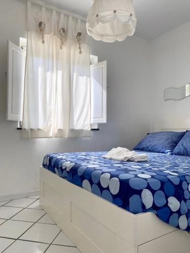 a bedroom with a blue and white bed and a chandelier at Dolcevita Villa in Vulcano in Vulcano