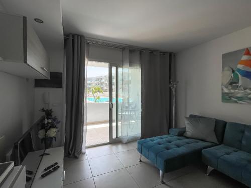 a living room with a blue couch and a sliding glass door at Paradise Palms I Deluxe, incl. Welcome Package in Corralejo
