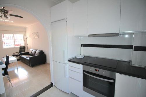 eine Küche mit weißen Schränken und ein Wohnzimmer in der Unterkunft Ground floor apartment Torrevieja Spain in Orihuela