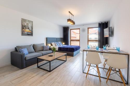 a living room with a couch and a table at Apartamenty Bałtyckie - Grand Baltic - WIFI, Klimatyzacja, Sala Zabaw, Taras wypoczynkowy, centrum Ustki in Ustka