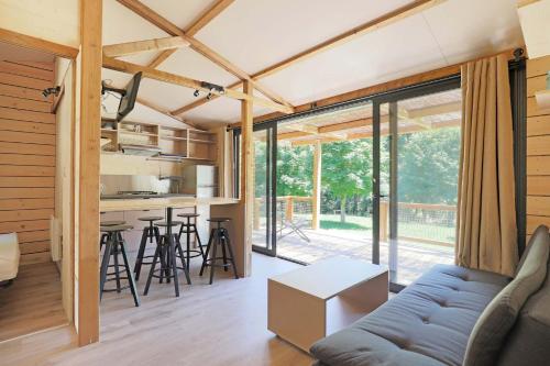 - un salon avec un canapé et une cuisine dans une maison dans l'établissement Domaine du Hygge Chalets Lodges & Spa, à Anould