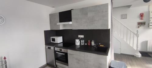 une cuisine avec un évier et un micro-ondes dans l'établissement Maison Pleubian mer à pied, à Pleubian