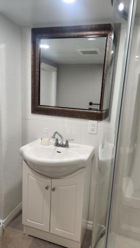 a white bathroom with a sink and a mirror at Dieppe Apartment in Dieppe