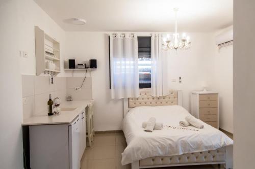 Dormitorio blanco pequeño con cama y lavamanos en Hadas Villa Spa Yavne'el by Sea N' Rent, en Yavneʼel