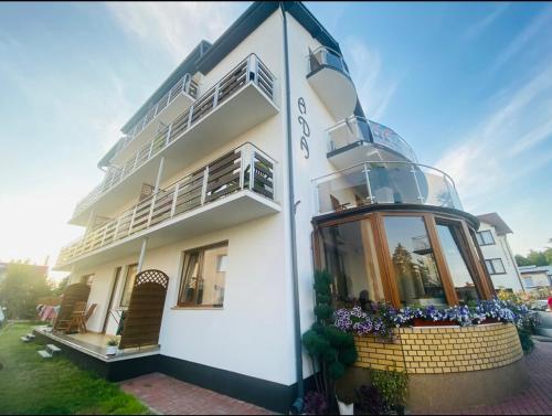 un edificio blanco con ventanas y flores delante de él en Willa Ada, en Karwia