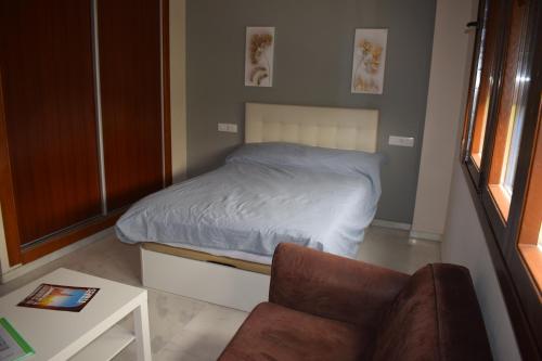 um pequeno quarto com uma cama e uma cadeira em Estudio Fibes-Palacio em Sevilha