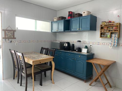 a kitchen with blue cabinets and a table with chairs at Duplex agradável com Ar, Internet, Netflix e Estacionamento in Campina Grande