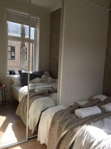 1 dormitorio con 2 camas y espejo en Newly renovated apt in the heart of Grünerløkka, en Oslo