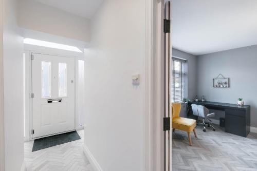 a hallway with a door and a desk with a chair at 6 Bedroom and 4 Bath Bedford House + Private Garden in Ruislip