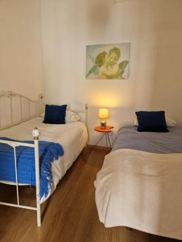 a bedroom with two beds and a table with a lamp at Casa Gil Vicente in Évora