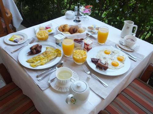 a table with plates of breakfast foods and orange juice at Tiki Hôtel - Hôtel d'application du Lycée de Tahiti in Punaauia