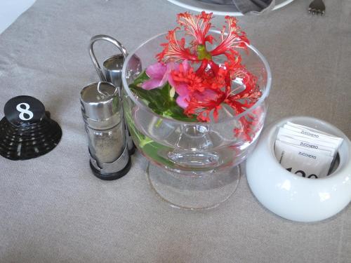 a glass vase with flowers in it on a table at Tiki Hôtel - Hôtel d'application du Lycée de Tahiti in Punaauia
